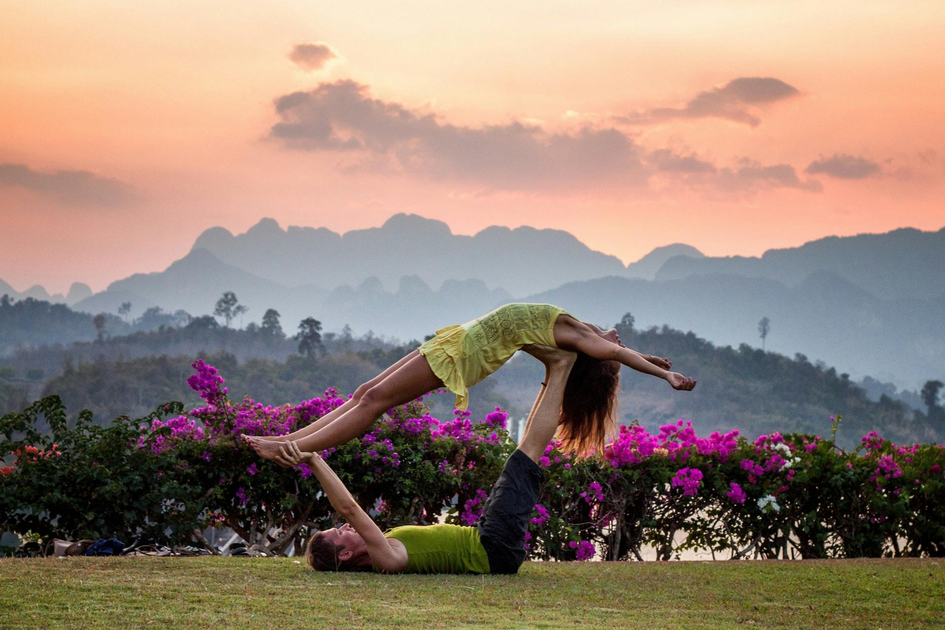 Two people doing acroyoga in front of mountains.